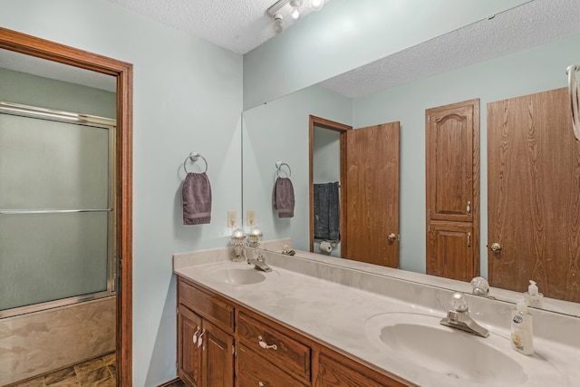 bathroom with a textured ceiling, double vanity, and a sink