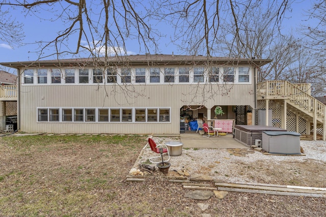 back of house with stairs, a deck, a patio area, and a hot tub