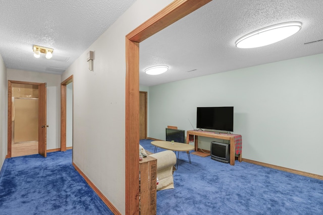 hallway with baseboards, visible vents, carpet floors, and a textured ceiling