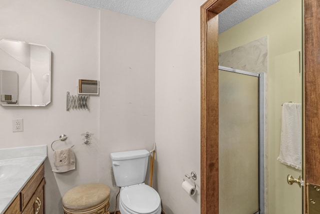 full bathroom with vanity, a shower stall, toilet, and a textured ceiling