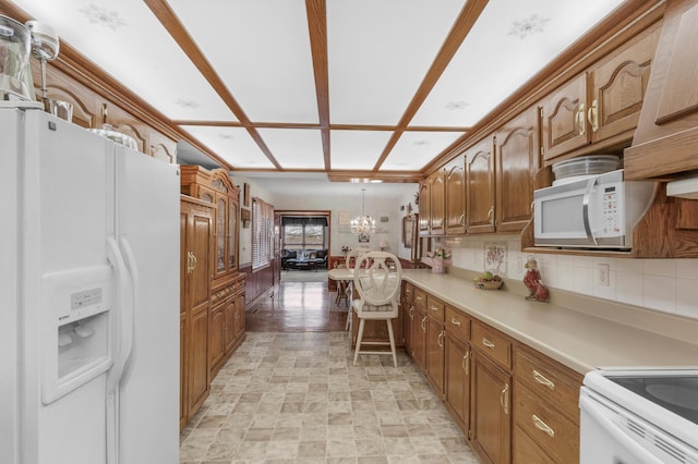 kitchen featuring white appliances, brown cabinets, a chandelier, and light countertops