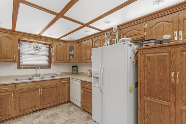 kitchen featuring decorative backsplash, brown cabinets, white appliances, and a sink