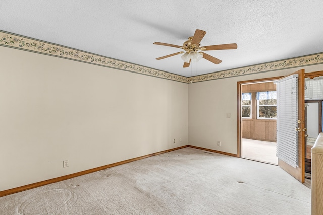 carpeted empty room featuring baseboards, a textured ceiling, and a ceiling fan