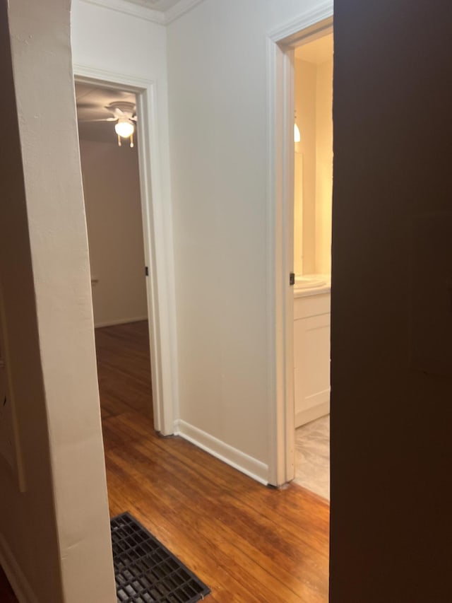 hall with baseboards, visible vents, and wood finished floors