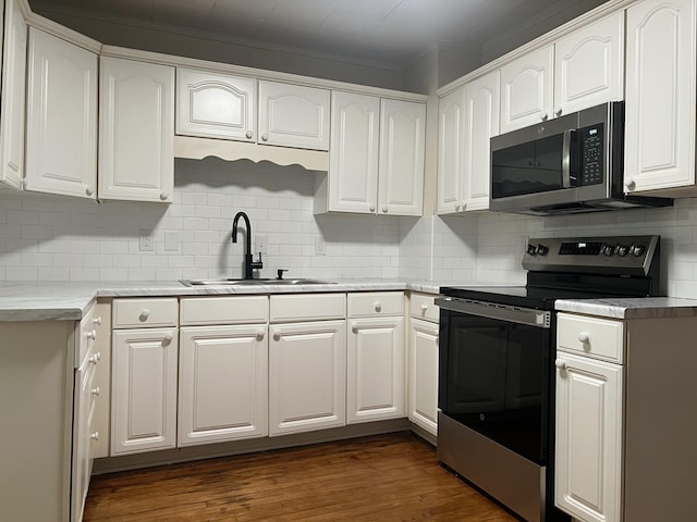 kitchen with appliances with stainless steel finishes, dark wood-type flooring, light countertops, white cabinetry, and a sink