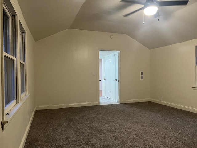 bonus room with vaulted ceiling, ceiling fan, dark carpet, and baseboards