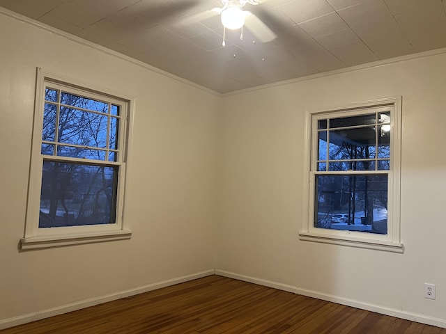 unfurnished room featuring ornamental molding, dark wood-type flooring, and baseboards