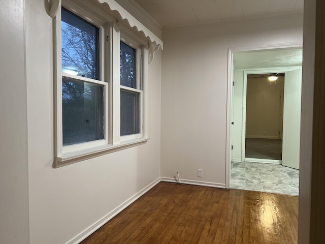 empty room featuring baseboards and dark wood-type flooring