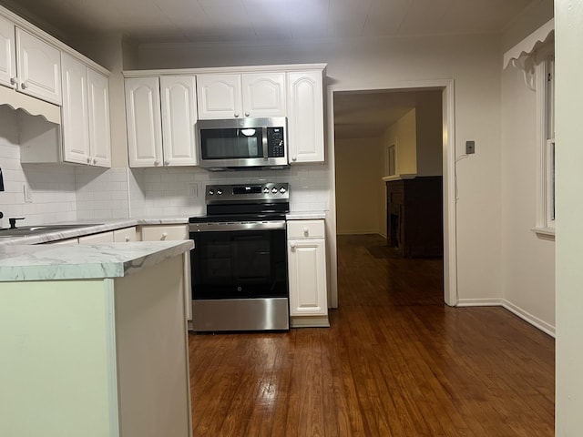 kitchen with dark wood-style floors, light countertops, decorative backsplash, appliances with stainless steel finishes, and white cabinetry