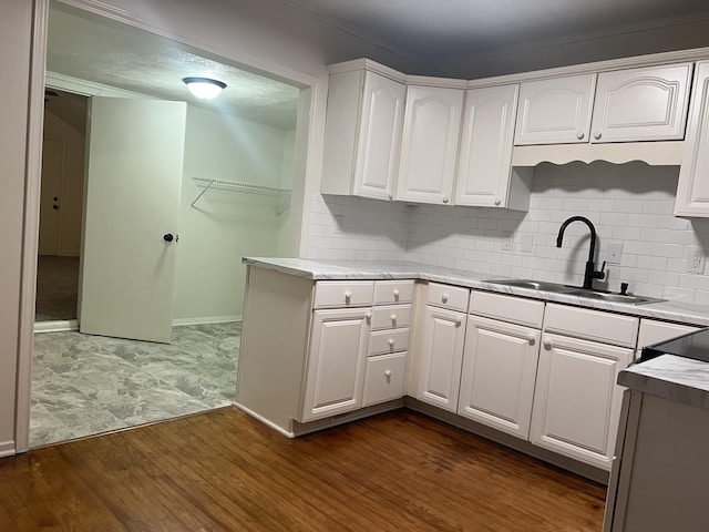 kitchen with light countertops, dark wood finished floors, a sink, and white cabinetry