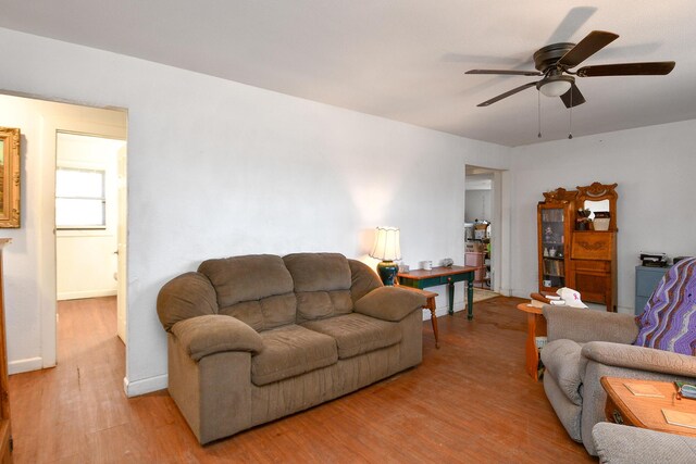 living area with baseboards, a ceiling fan, and light wood-style floors