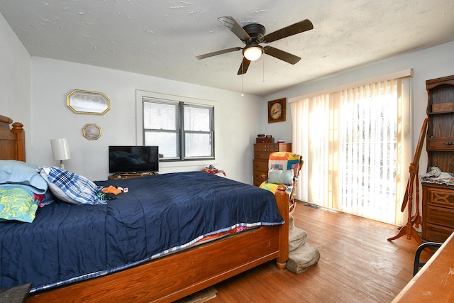 bedroom with multiple windows, ceiling fan, a textured ceiling, and wood finished floors