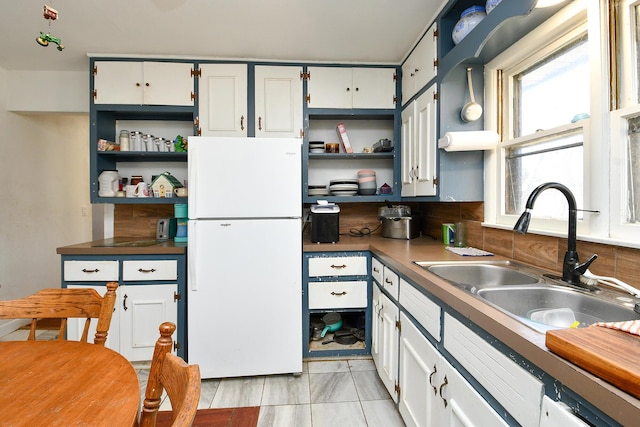 kitchen with open shelves, a sink, freestanding refrigerator, and white cabinets