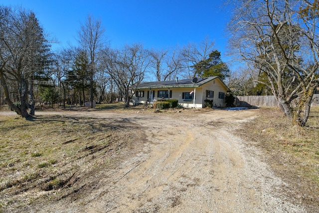 ranch-style home featuring driveway and fence