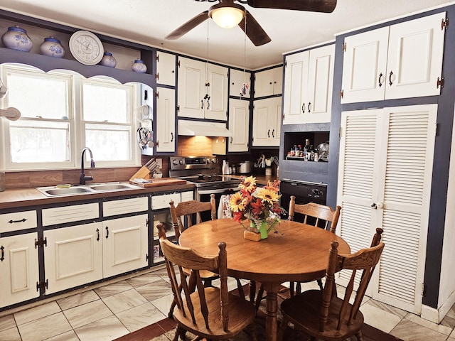 kitchen with stainless steel electric stove, a ceiling fan, white cabinets, a sink, and under cabinet range hood