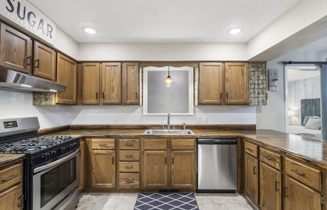 kitchen featuring dark countertops, a peninsula, stainless steel appliances, and a sink