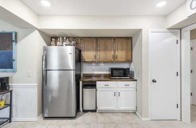 kitchen featuring recessed lighting, decorative backsplash, brown cabinetry, freestanding refrigerator, and white cabinetry