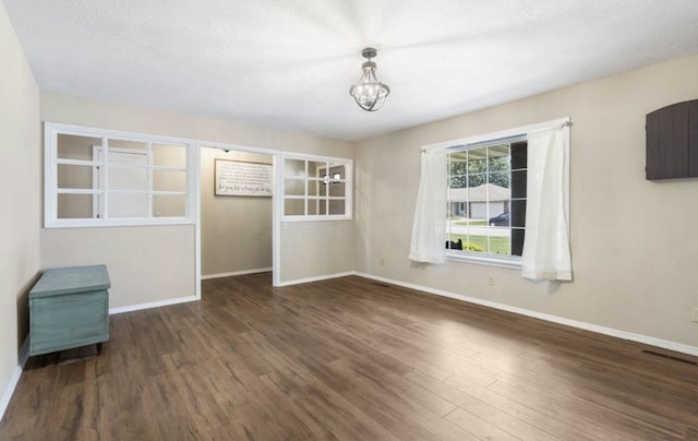 unfurnished room featuring dark wood-type flooring, visible vents, and baseboards