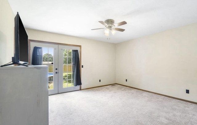 spare room with light carpet, ceiling fan, baseboards, and french doors