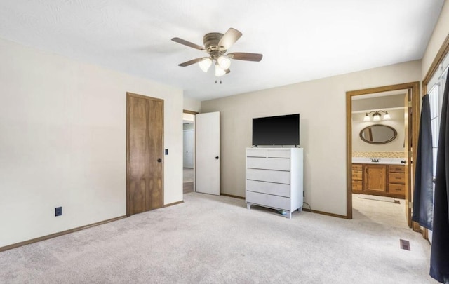 unfurnished bedroom with light carpet, baseboards, and ensuite bathroom