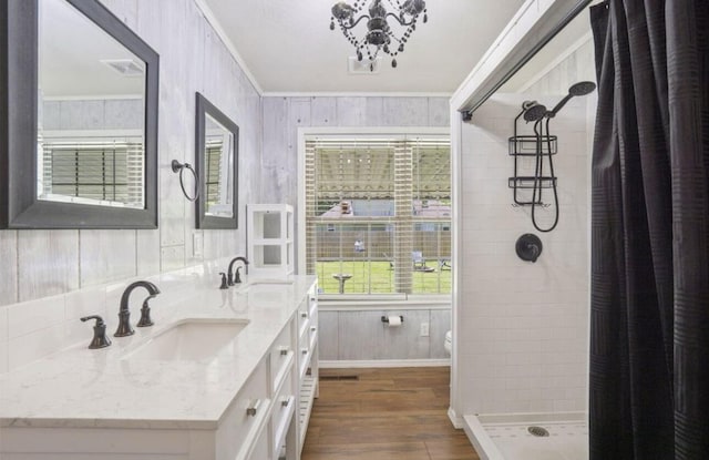 full bath with ornamental molding, a stall shower, a sink, and wood finished floors