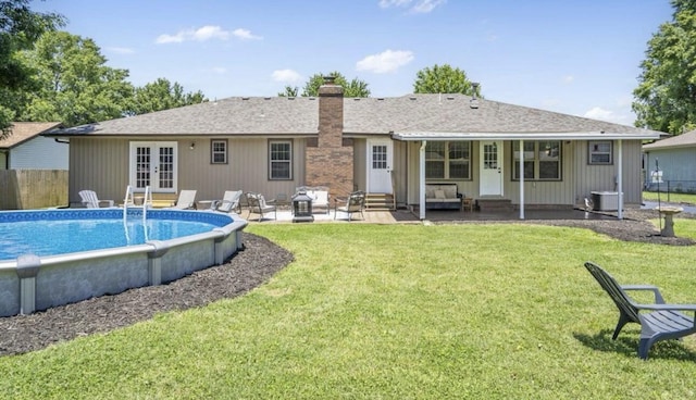 back of house featuring entry steps, an outdoor pool, a lawn, a chimney, and french doors