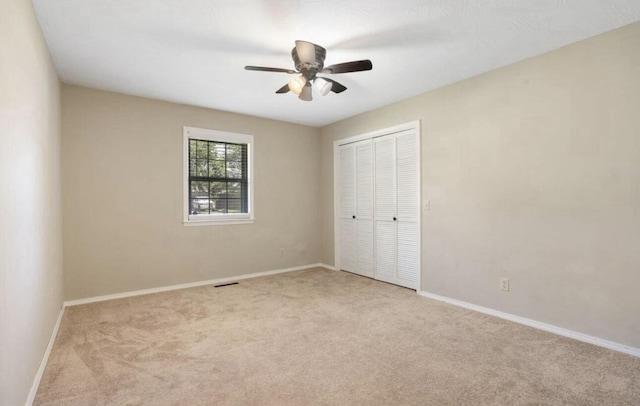 unfurnished bedroom featuring baseboards, a closet, visible vents, and light colored carpet