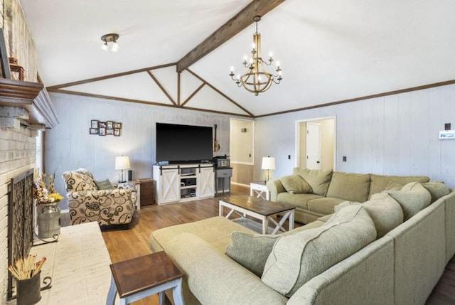 living room featuring lofted ceiling with beams, wood finished floors, crown molding, a brick fireplace, and a notable chandelier