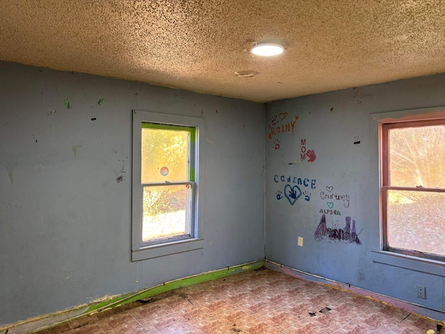 spare room with a textured ceiling and baseboards