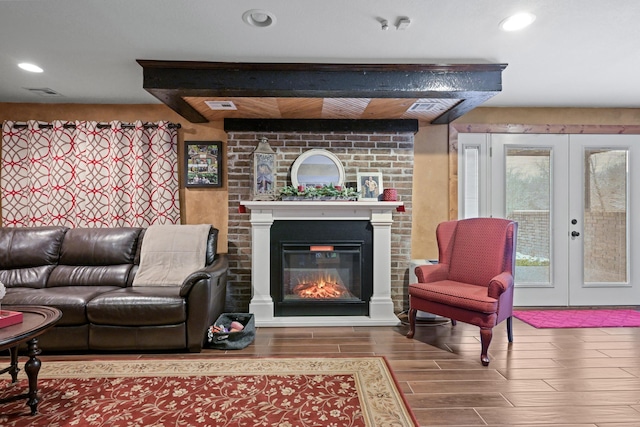 living area with recessed lighting, wood finish floors, a fireplace, visible vents, and french doors