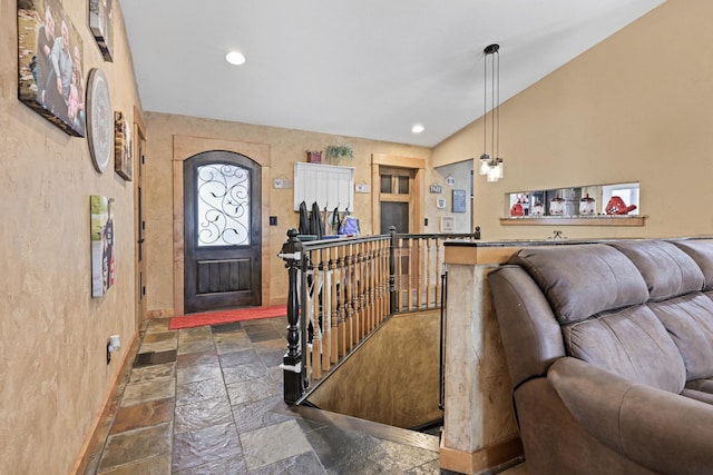 entryway with vaulted ceiling, stone tile flooring, and recessed lighting