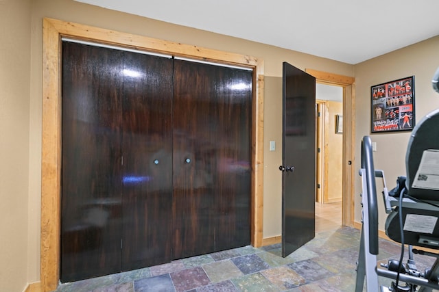 bedroom with baseboards, stone finish floor, and a closet