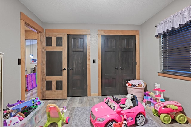 rec room with light wood-style flooring and a textured ceiling