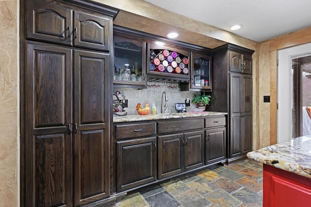 bar with tasteful backsplash, recessed lighting, stone tile flooring, a sink, and wet bar