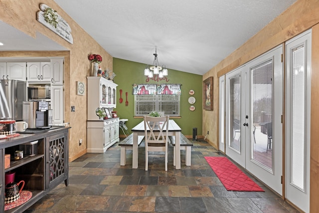 dining room featuring french doors, stone tile flooring, an inviting chandelier, vaulted ceiling, and baseboards