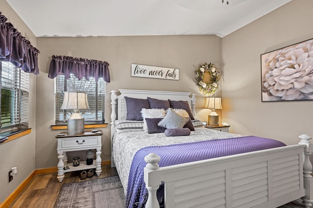 bedroom with dark wood-style floors, vaulted ceiling, and baseboards