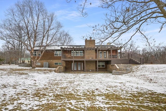 snow covered house with stairs, central AC unit, and a chimney