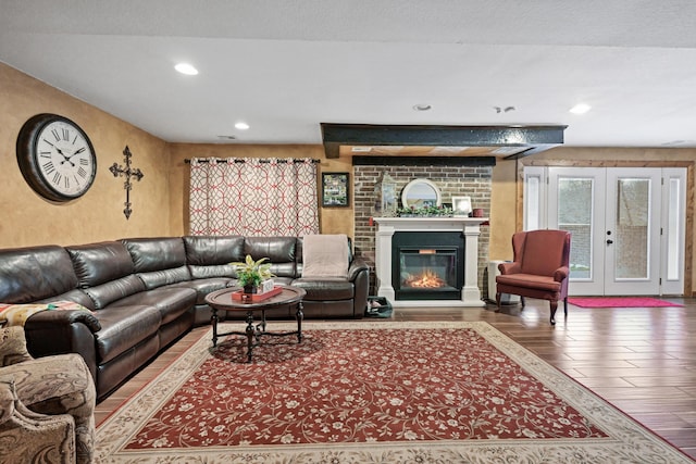 living area featuring french doors, recessed lighting, a brick fireplace, a textured ceiling, and wood finished floors