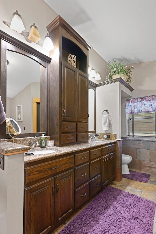 full bath featuring a sink, toilet, and double vanity