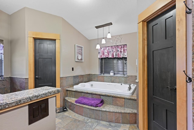 bathroom with stone finish floor and a bath