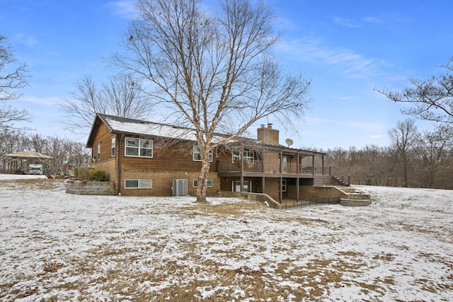 snow covered rear of property featuring a chimney