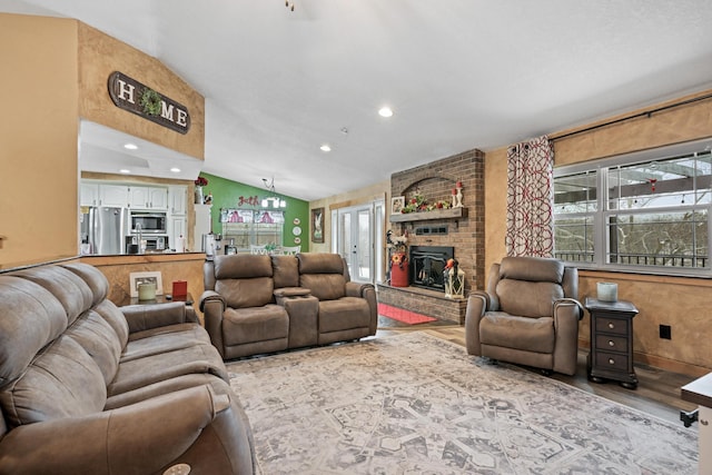 living area with vaulted ceiling, recessed lighting, a brick fireplace, and light wood-style floors