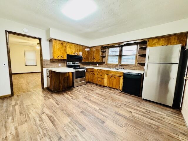 kitchen with light wood-style floors, decorative backsplash, stainless steel appliances, and light countertops