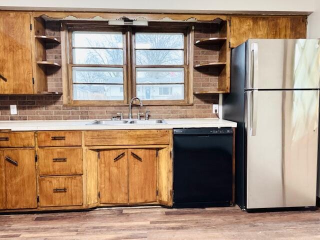 kitchen with a sink, light countertops, freestanding refrigerator, dishwasher, and open shelves