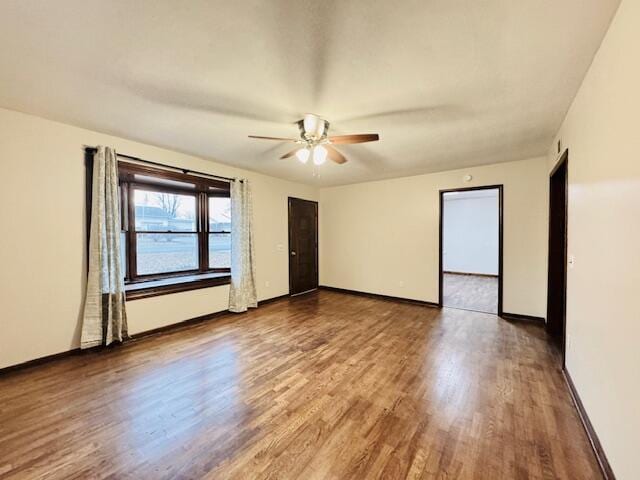 empty room featuring ceiling fan, wood finished floors, and baseboards