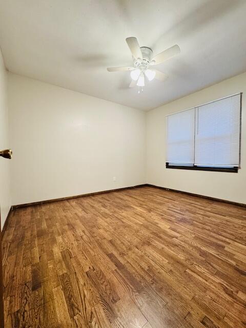 empty room with ceiling fan, baseboards, and wood finished floors