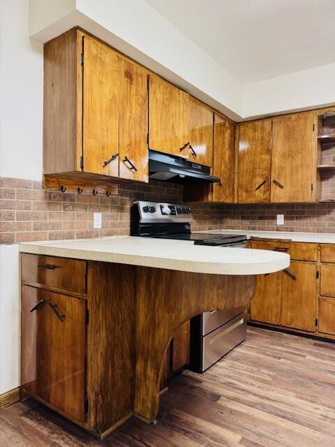 kitchen with light countertops, decorative backsplash, wood finished floors, under cabinet range hood, and stainless steel electric range