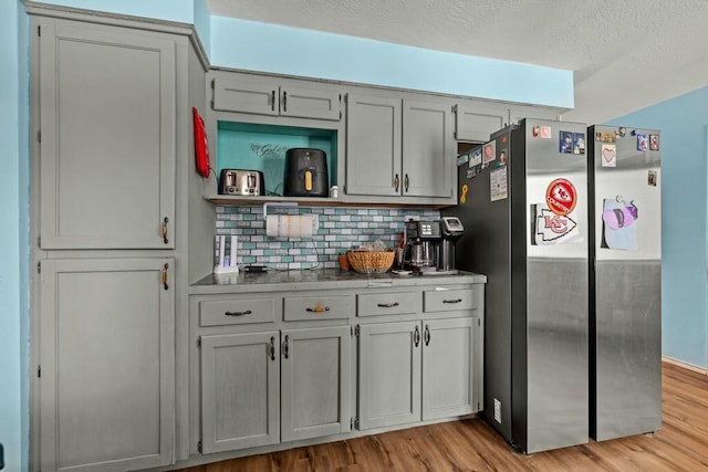 kitchen with light wood-style flooring, freestanding refrigerator, open shelves, and gray cabinetry