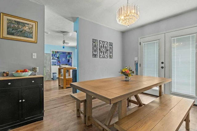 dining room with light wood-style floors, french doors, and a notable chandelier