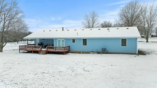 snow covered house with a deck and cooling unit